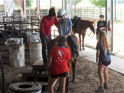 People help child get positioned on a saddle
